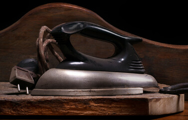 Old electric iron for clothes covered with dust and resting on a rustic wooden base