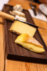 Plate of fancy cheeses on a narrow wood board in a restaurant