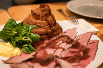 Deconstructed roast beef sandwich with croissant, arugula, reduced au jus, and aioli