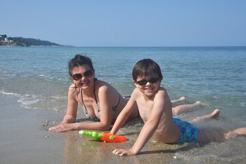 Happy family enjoy at beach. Summer vacation, smiling and joy in water. Mom with the small son on beach in the sea waves