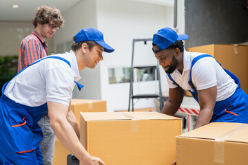 Man movers worker in blue uniform unloading cardboard boxes from truck.Professional delivery and...