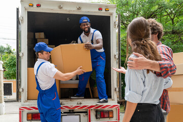 Man movers worker in blue uniform unloading cardboard boxes from truck.Professional delivery and...