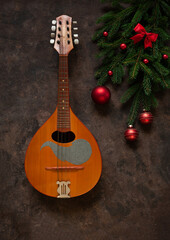 Old mandolin and fir-tree branches with Christmas decor. Christmas and New Year's concept. Top view, close-up on dark concrete background...
