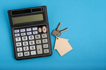 Calculator and keychain with house keys blue background.Concept mortgages, buying and renting housing.