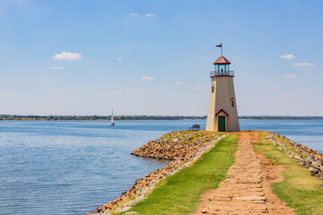 Sunny view of the Lake Hefner lighthouse with a sailing boat
