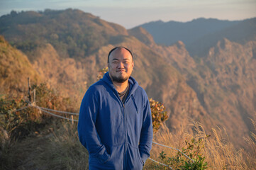 Asian fat man with beautiful sunrise of khao San nok wua mountain kanchanaburi.Khao San Nok Wua is...