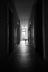 Bright sunlight shines through distant window in a dark and spooky hallway.