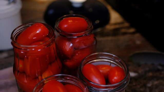 dill pour hot water in a glass jar with tomatoes. Homemade pickled canned red tomato with herbs. Home preservation.