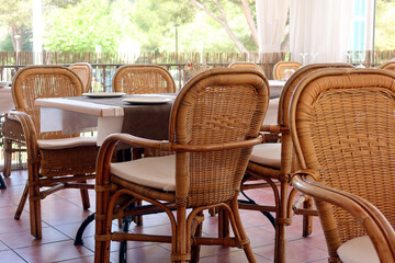 Outdoor tables and chairs, empty beach restaurant table. Rattan style furniture in the restaurant