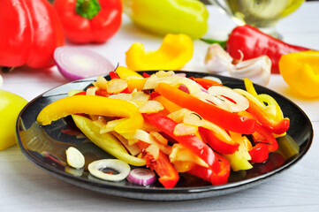 Bell pepper salad on a black plate.