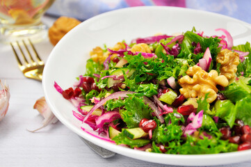Healthy vegetarian Salad with pomegranate, walnuts and lettuce leaves.