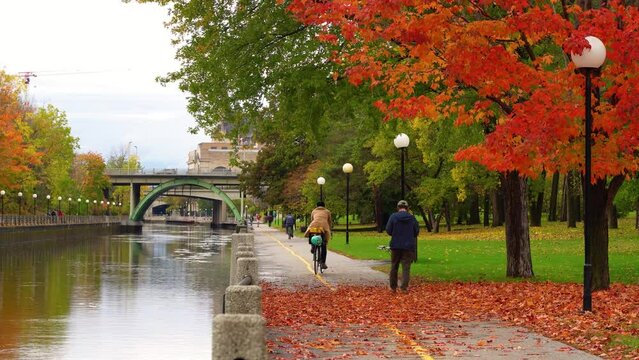 People cycling and walking in Rideau Canal Eastern Pathway. Autumn scenery in Ottawa, Ontario, Canada.