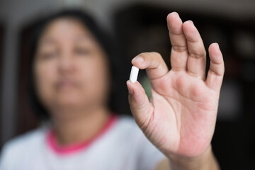 Close up woman hand putting white pill.Sick female holding pill for taking medicines, antidepressant, painkiller or antibiotic.Pharmacy and healthcare concept.Patient with pill at home.