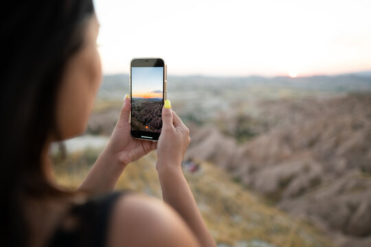 a tourist takes pictures of the sunset in the mountains on a mobile phone