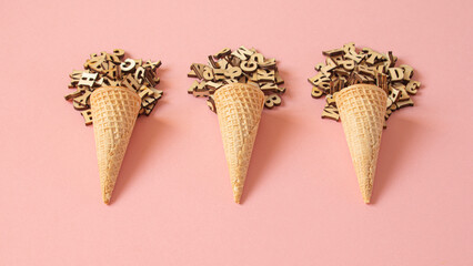 Three cone ice creams formed with a ball of wooden letters on a pink background