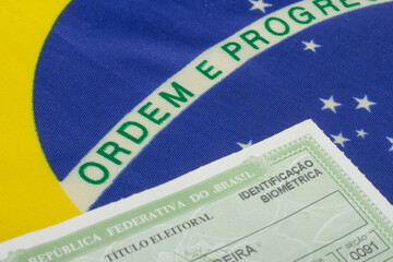 Obraz premium LAURO DE FREITAS, BRAZIL - August 19, 2022 : hand holding brazilian election document near brazilian flag