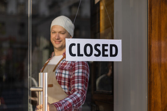 Handsome Bar Owner Standing Near Sign Board CLOSED, Which Hanging On Door Of Cafe.