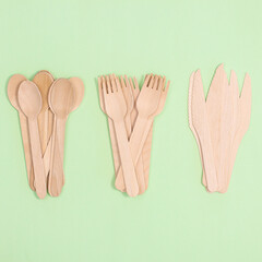 Wooden zero waste forks, knifes and spoons on pastel green background. Flat lay