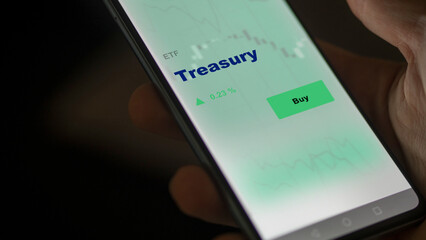 An investor's analyzing the Treasury etf fund on screen. A phone shows the ETF's prices treasury to invest