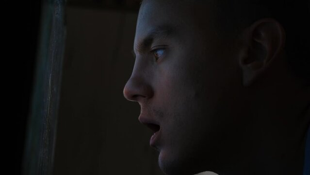 A man looks at the TV screen with his mouth open, close-up. Propaganda media concept