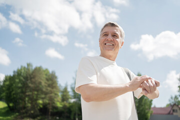 A retired man uses a fitness watch, a sporty man does a workout in the park.