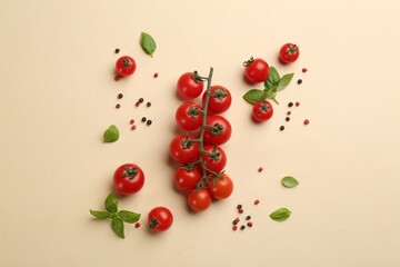Fresh cherry tomatoes, basil leaves and pepper grains on beige background, flat lay