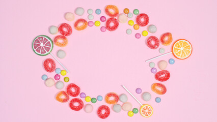 sweet candies and jelly beans make copy space frame on pastel pink background. Flat lay