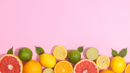 Citrus fruits with green leaves on bottom on pastel pink background with copy space. Flat lay