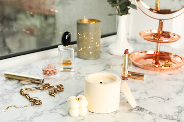 Burning soy candles, cosmetics and stylish accessories on white window sill indoors