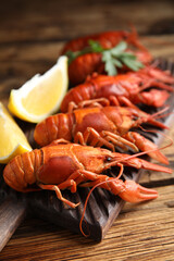 Delicious boiled crayfishes on wooden table, closeup