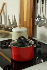 Red pot on electric stove in kitchen. Cooking utensil