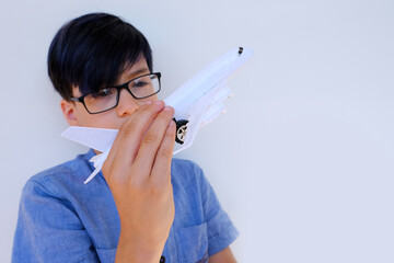 child, a boy of 10 years old in a blue shirt, holds model airplane, a plastic toy, plays with it, concept of vacation, long journey, air travel, transportation, transport, dreaming about holidays