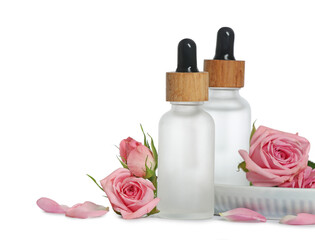 Bottles of essential rose oils and flowers on white background