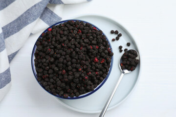 Bowl and spoon with dried blueberries on white wooden table, top view