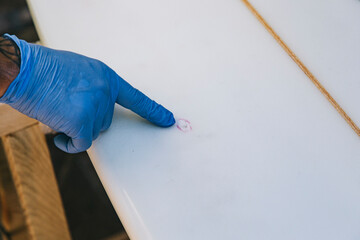 Close up of hands pointing out the blow to repair on a surfboard