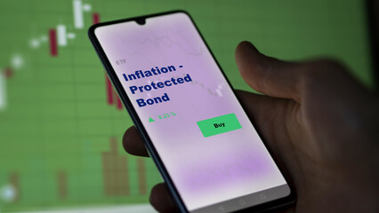 An investor's analyzing the inflation-protected bond etf fund on a screen. A phone shows the prices of bonds protected against inflation.	
