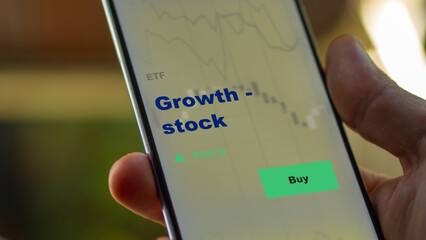 An investor's analyzing the growth - stock etf fund on screen. A phone shows the growth-stock ETF's prices growth stock to invest.