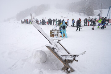 A queue of skiers and snowboarders at the T-bar at the ski resort. Blizzard. Copy space.