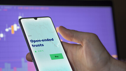 An investor's analyzing the open-ended trusts etf fund on screen. A phone shows the ETF's prices...