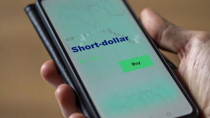 An investor's analyzing the short-dollar etf fund on screen. A phone shows the short-dollar ETF's prices to invest