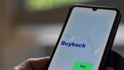 An investor's analyzing the buyback etf fund on screen. A phone shows the ETF's prices repurchased stocks shares buy back to invest in funds.