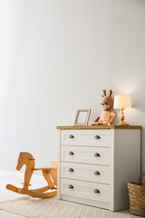 Modern white chest of drawers near light wall in child room. Interior design