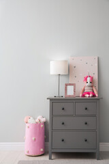 Modern grey chest of drawers near light wall in child room. Interior design