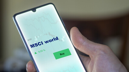 An investor's analyzing the MSCI world etf fund on screen. A phone shows the ETF's prices msci world to invest