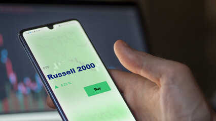 An investor's analyzing the Russell 2000 etf fund on screen. A phone shows the ETF's prices russell 2000 to invest