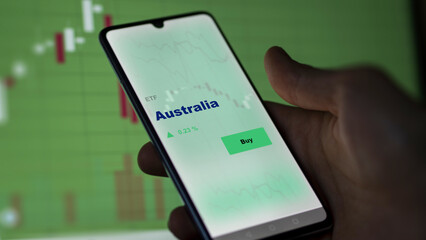 An investor's analyzing the Australia etf fund on screen. A phone shows the ETF's prices australian Australian australia to invest