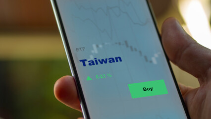 An investor's analyzing the Taiwan etf fund on screen. A phone shows the ETF's prices Taiwanese to invest