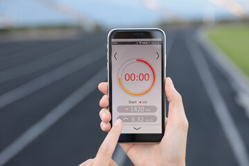 Young woman using fitness app on smartphone at stadium, closeup