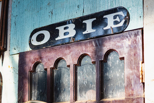 This is a digitally enhanced image of the transom of an antique door with the leters "OBIE" above it in white against a black background.  The transom is red.  The shadow on the wall is blue.