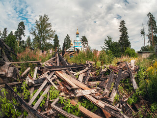 White new church behind the ruins. Pile of boards, the ruins of a village, a new life through faith.
